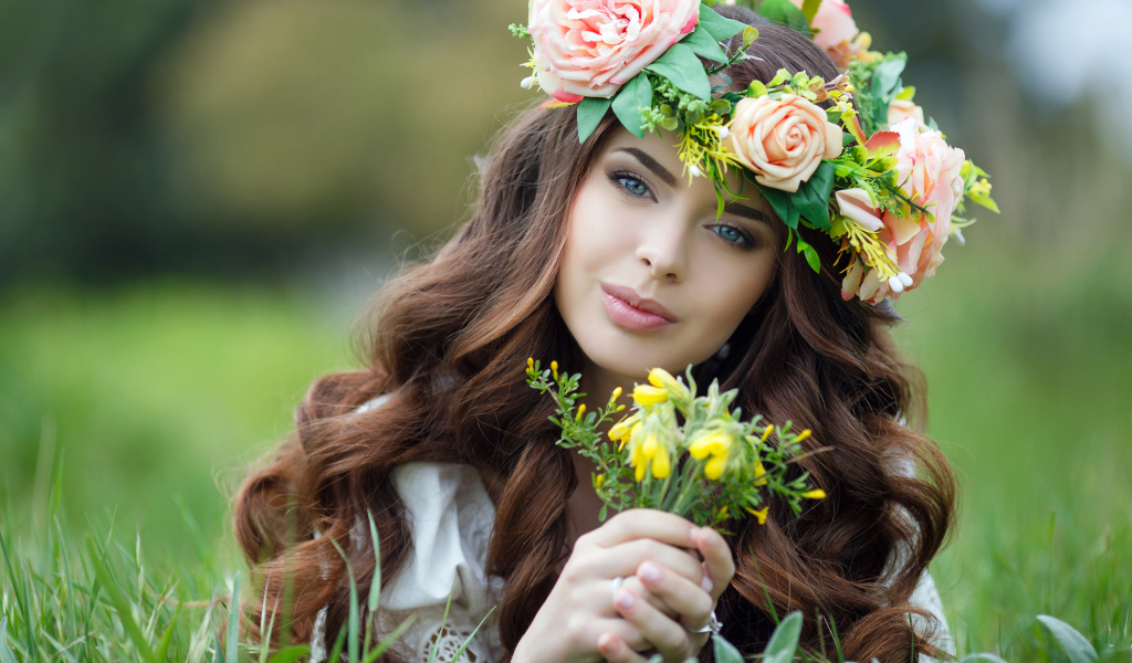 Красивая девушка с венком на голове лежит на траве