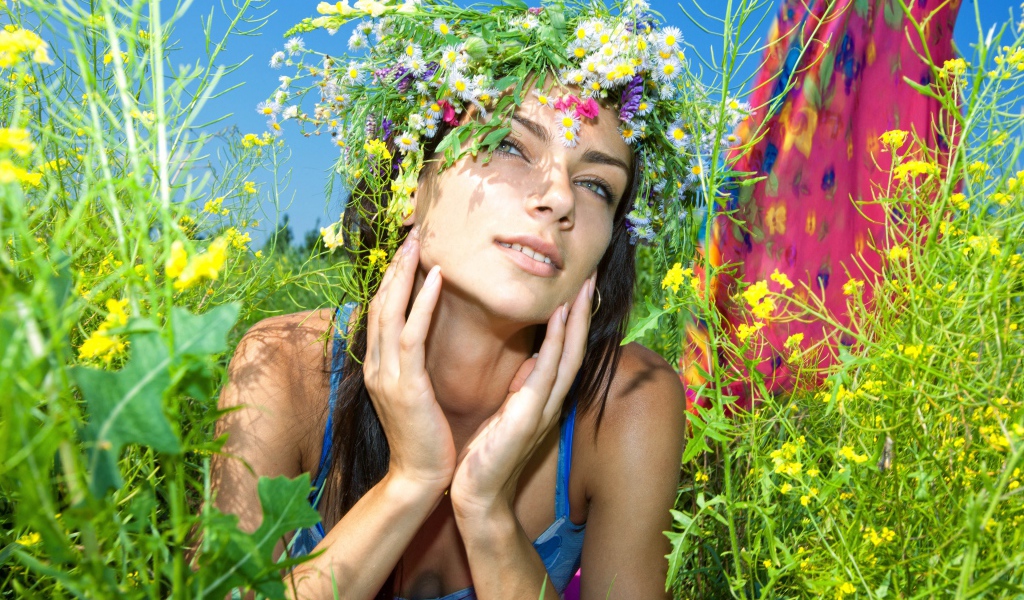 Молодая девушка с венком из полевых цветов лежит в траве