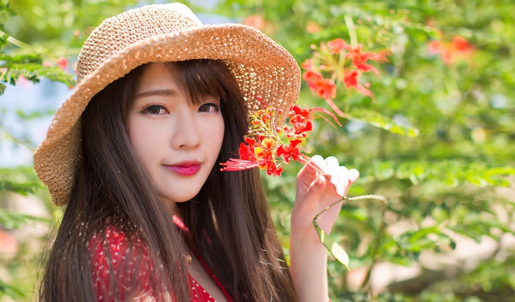 Девушка азиатка в шляпе с красным цветком