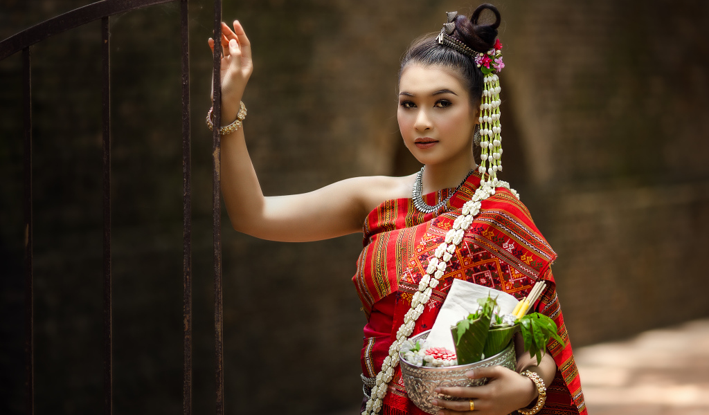 Девушка азиатка в костюме стоит у железных ворот