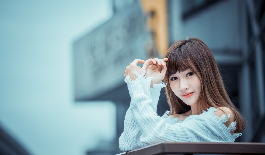 Молодая девушка азиатка в белом свитере на балконе