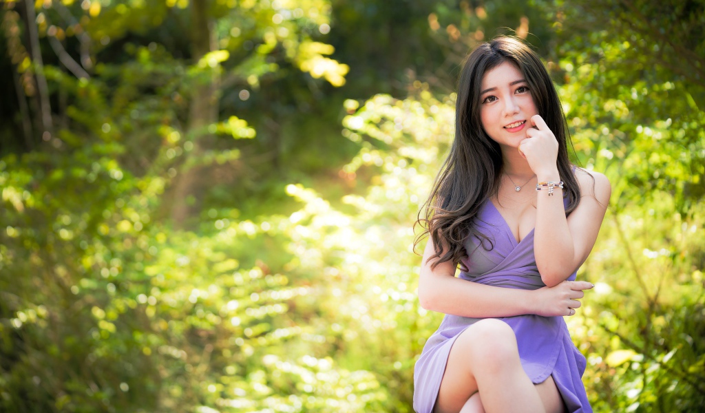 Молодая девушка азиатка сидит на лавке в парке