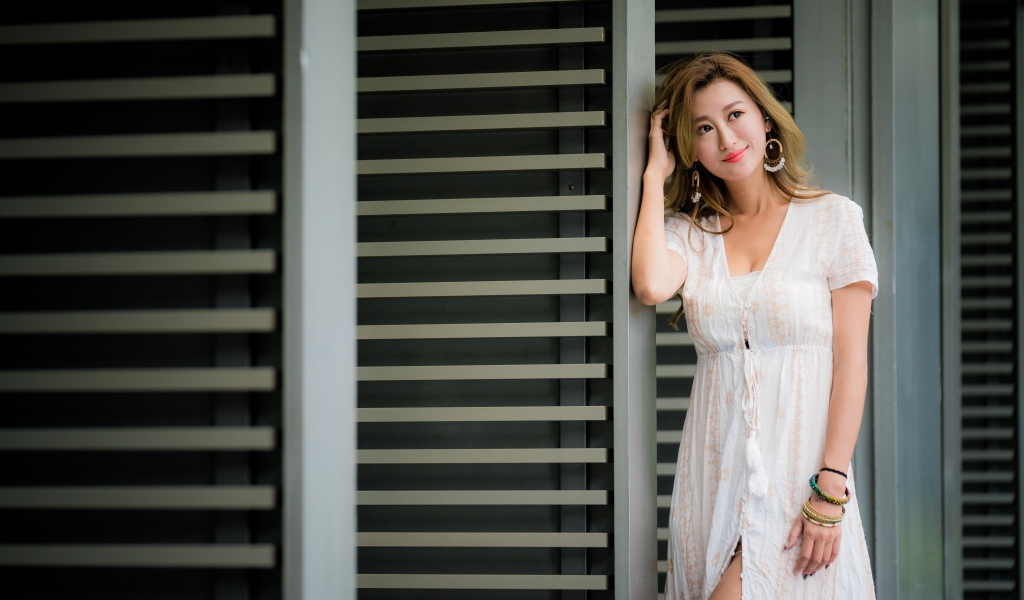 Красивая девушка азиатка в платье стоит у дверей