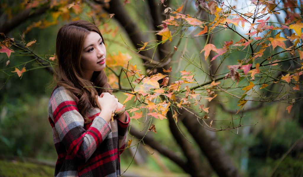 Красивая азиатка стоит у дерева