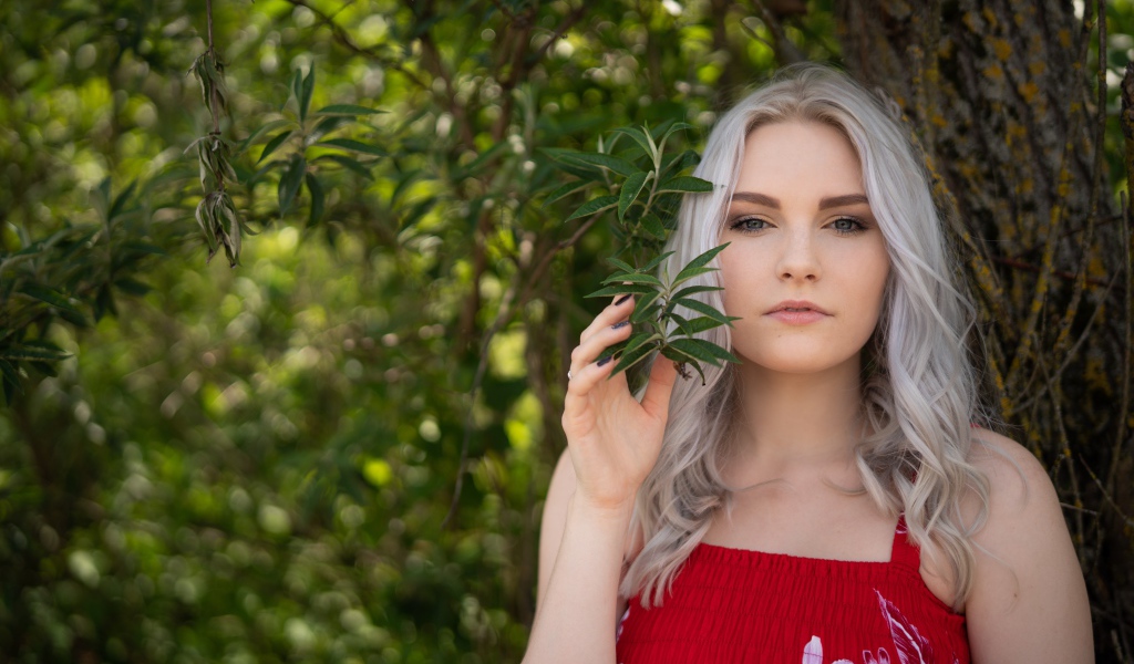 Красивая блондинка стоит у дерева 