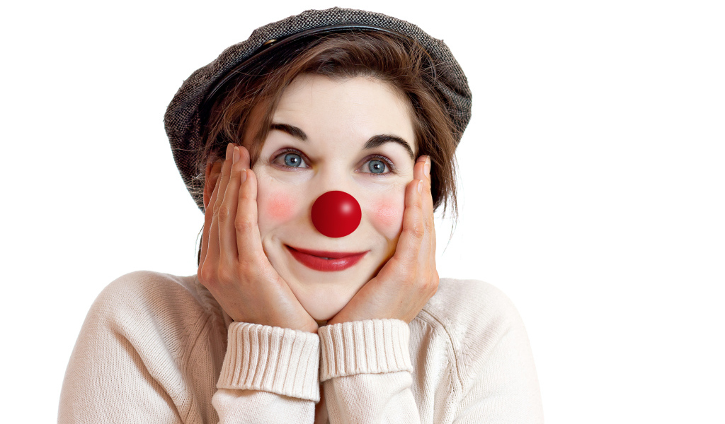 Красивая голубоглазая девушка в кепке с носом клоуна на белом фоне