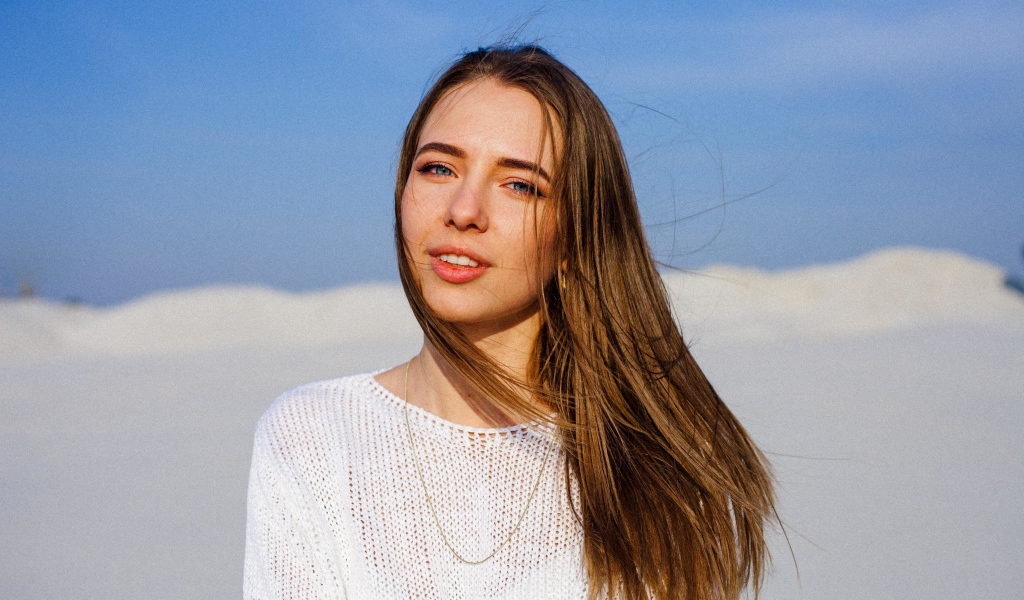 Красивая голубоглазая девушка в белом свитере на фоне голубого неба