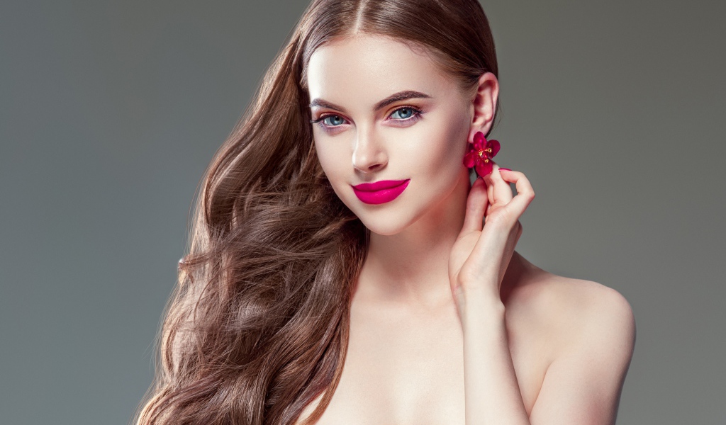 Красивая голубоглазая девушка с длинными волосами на сером фоне