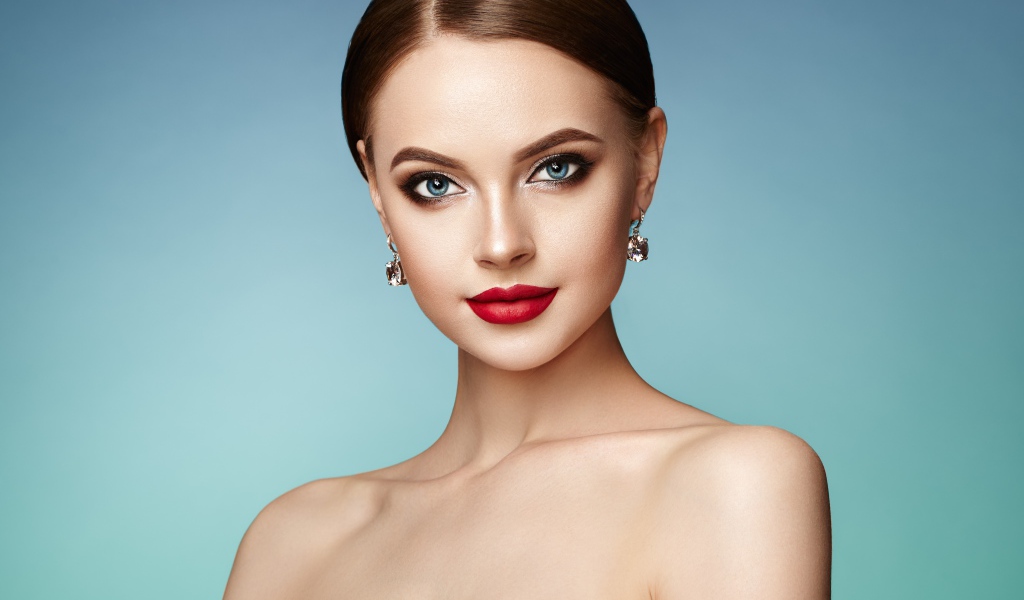 Красивая голубоглазая девушка с накрашенными губами и серьгами в ушах