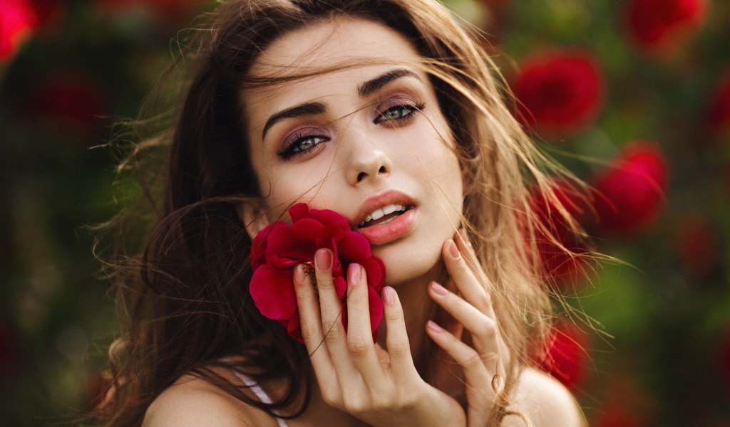 Красивая девушка шатенка с цветком у лица