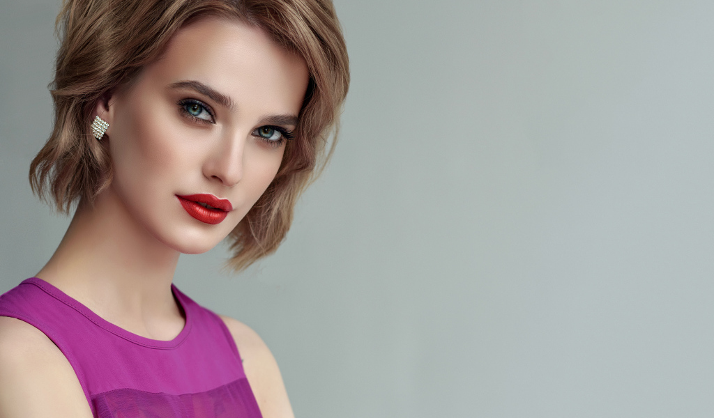 Красивая девушка шатенка с короткой стрижкой на сером фоне