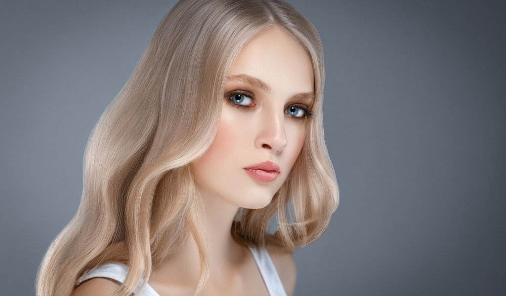 Красивая нежная голубоглазая блондинка на сером фоне
