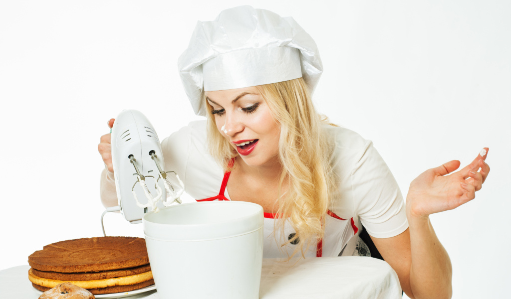 Красивая девушка повар взбивает крем для торта миксером