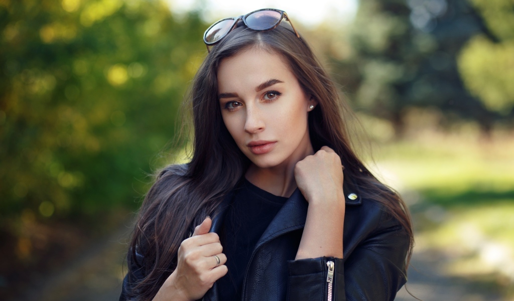 Красивая девушка в черной куртке с очками на голове