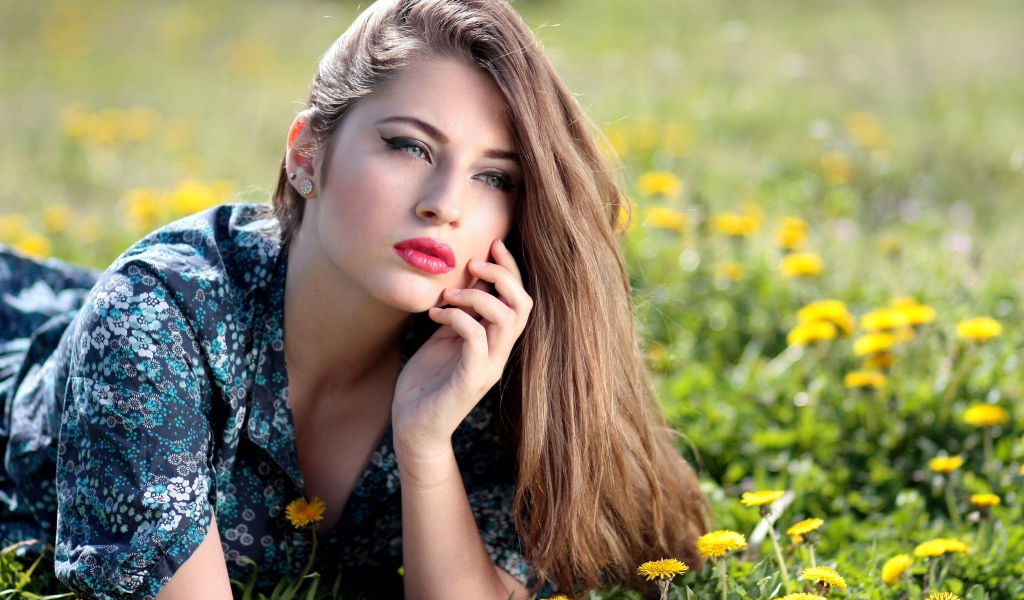 Красивая девушка в платье лежит на траве с одуванчиками