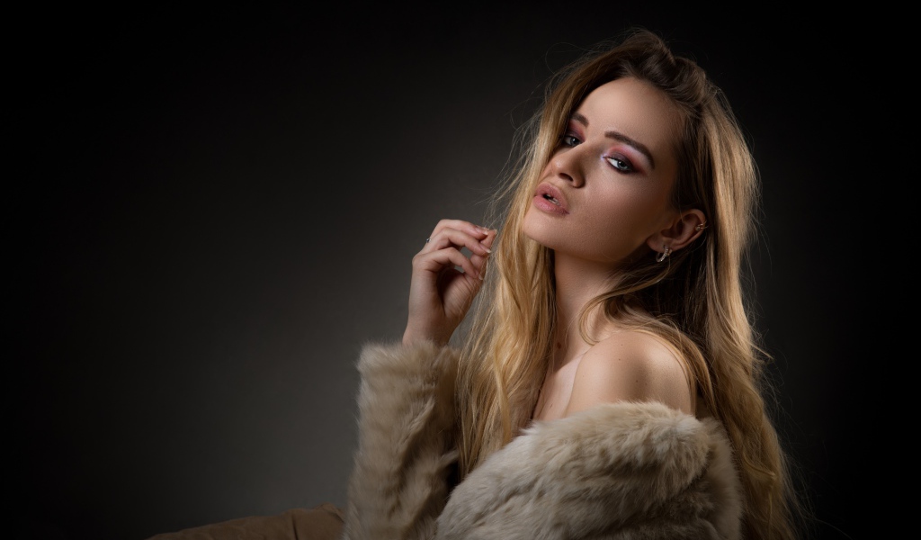 Красивая девушка в шубе на сером фоне