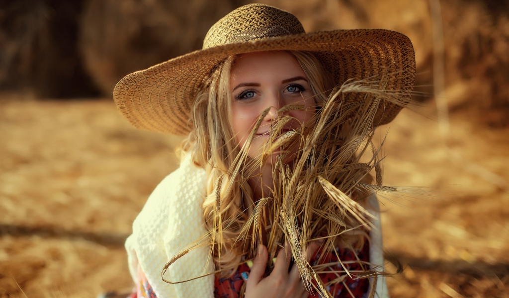 Красивая девушка в шляпе с колосьями в руке