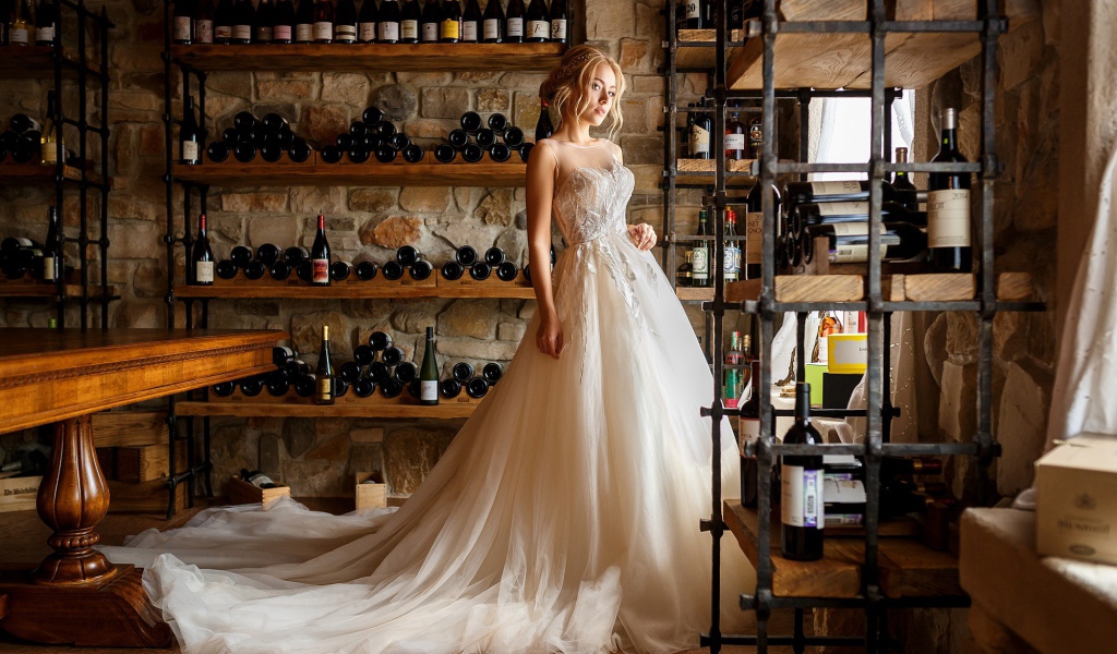 Красивая девушка в пышном свадебном платье в винном погребе