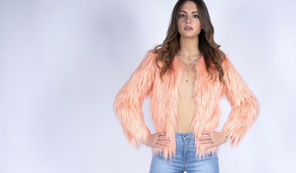 Красивая девушка в розовой шубе и джинсовых шортах