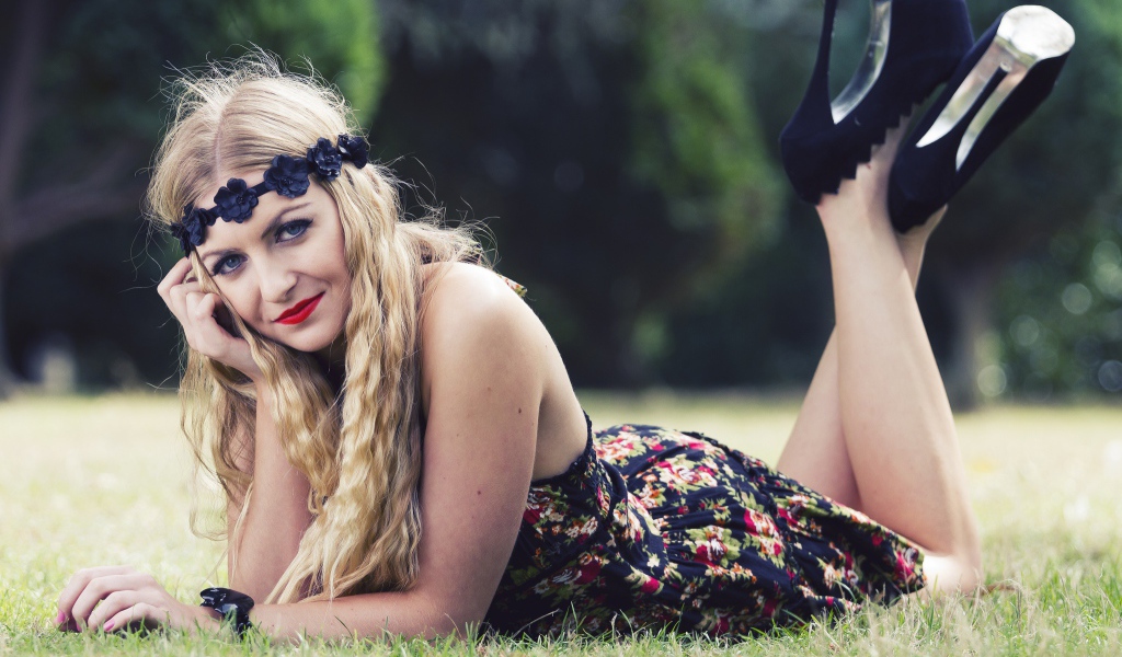 Красивая девушка в черных туфлях лежит на зеленой траве