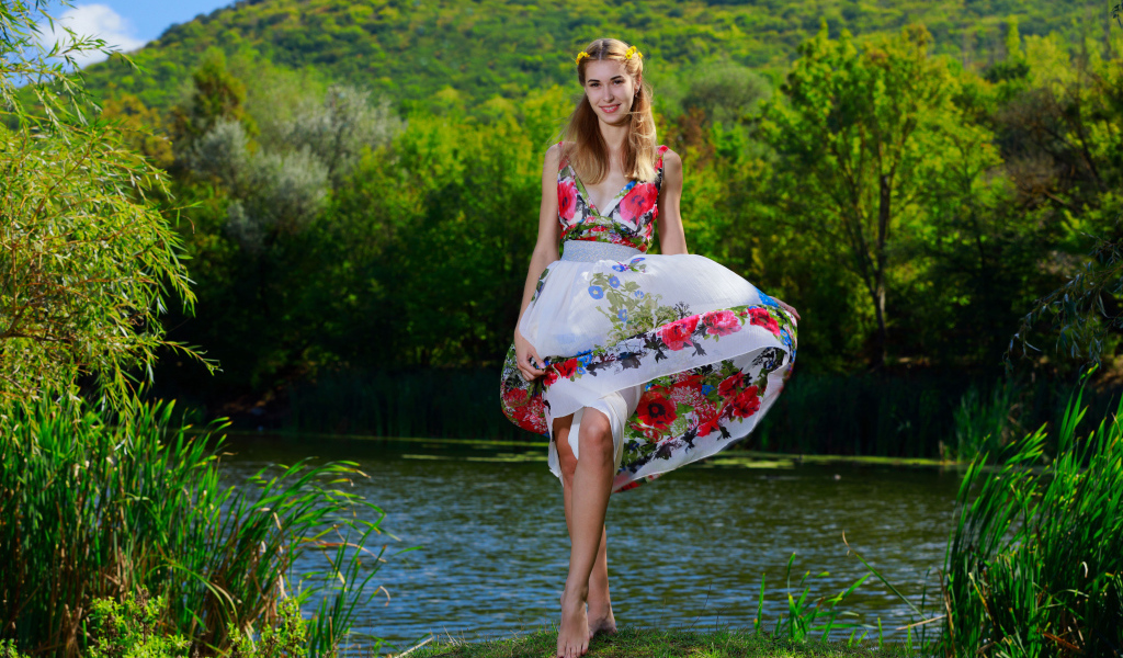 Красивая девушка в платье у реки на фоне леса 