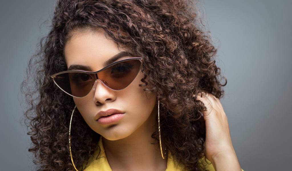 Красивая девушка в солнечных очках на сером фоне