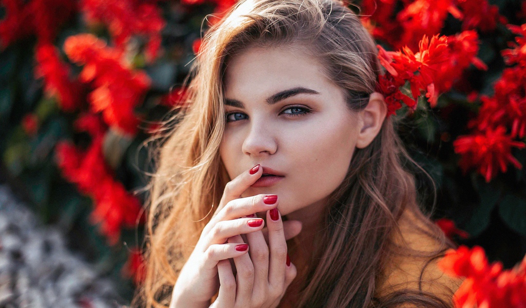 Красивая девушка на фоне красных цветов