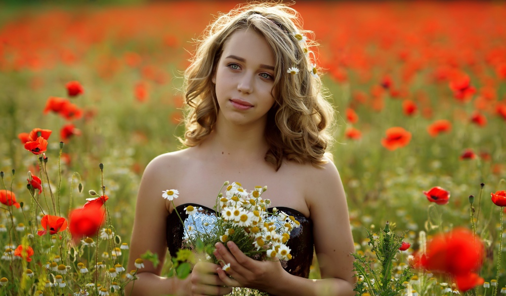 Красивая девушка с букетом ромашек на поле с маками