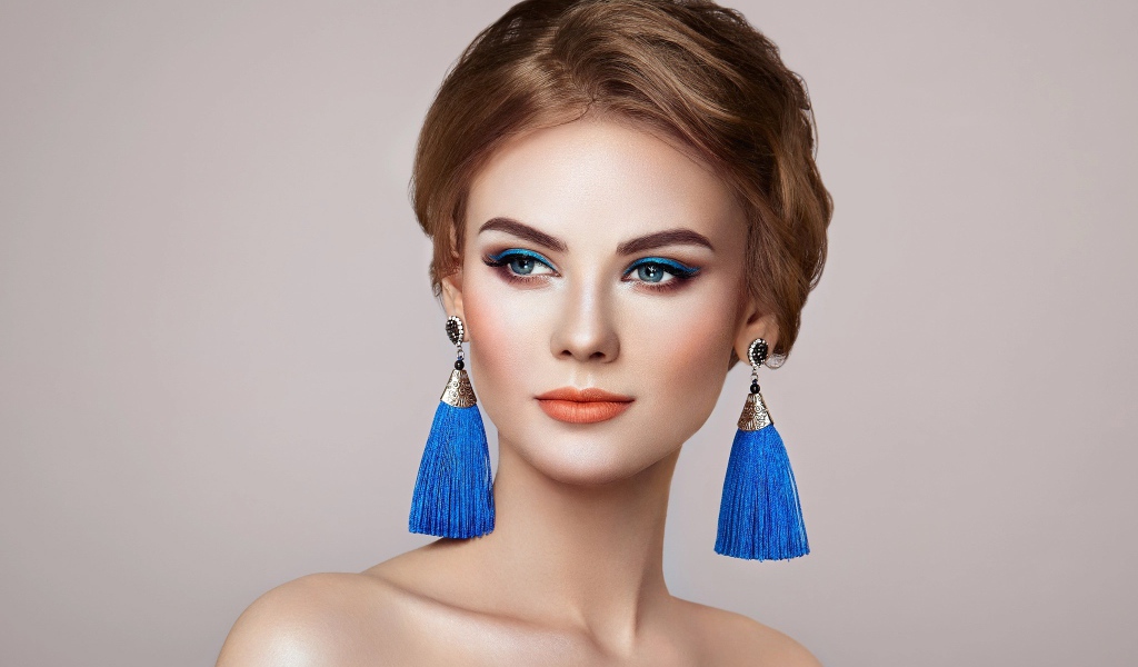 Красивая девушка с синими сережками на сером фоне