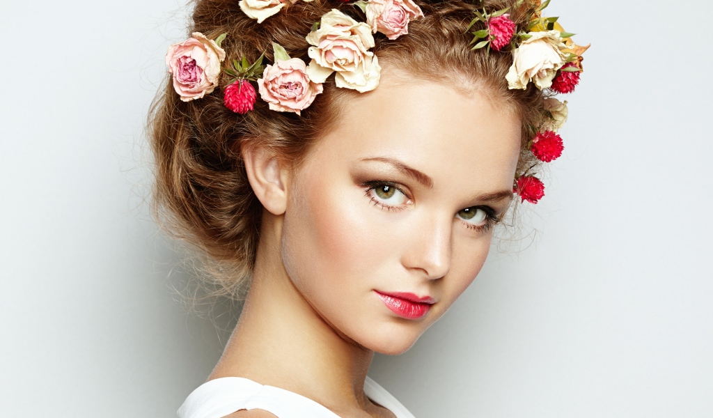 Красивая девушка с цветами в волосах на сером фоне