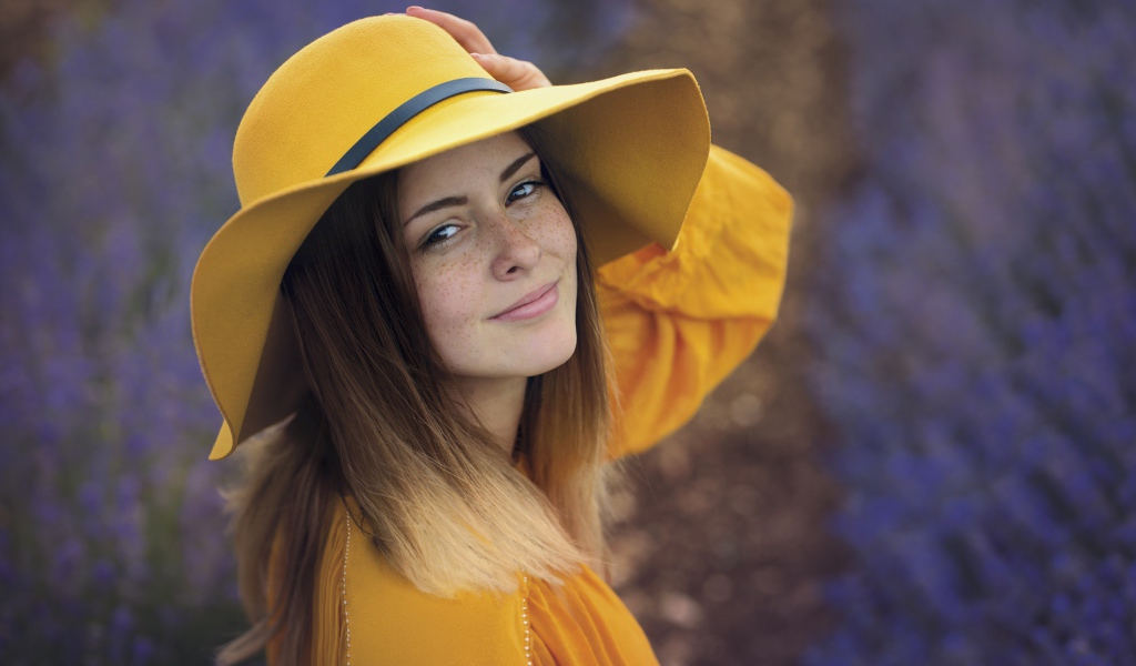 Красивая девушка с веснушками на лице в желтой шляпе