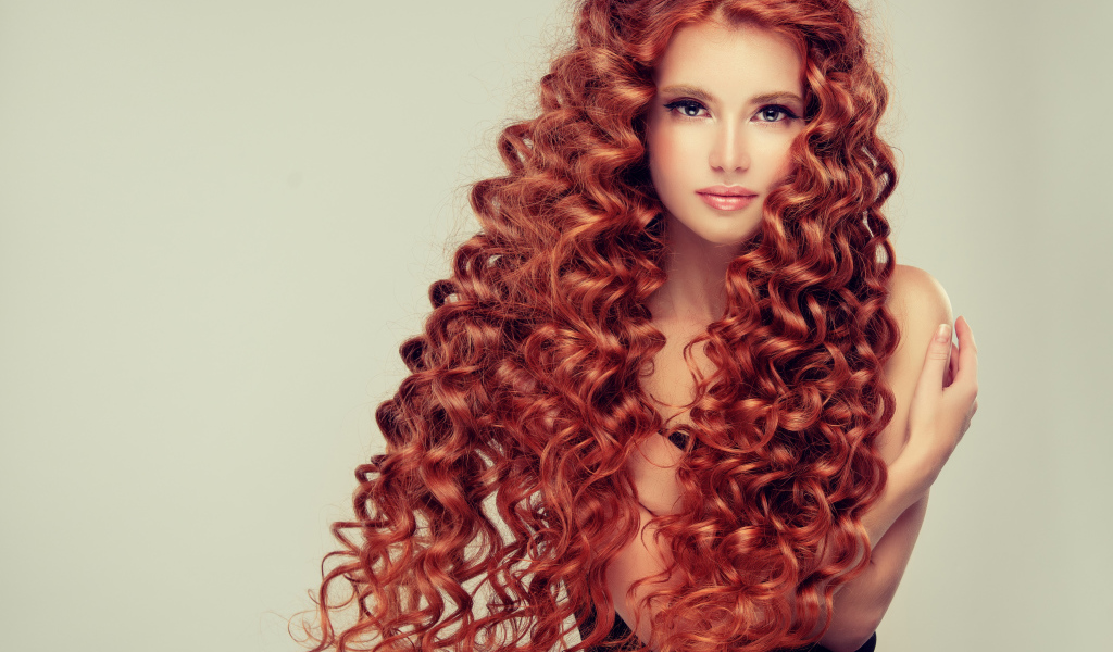 Красивая девушка с длинными рыжими волосами на сером фоне