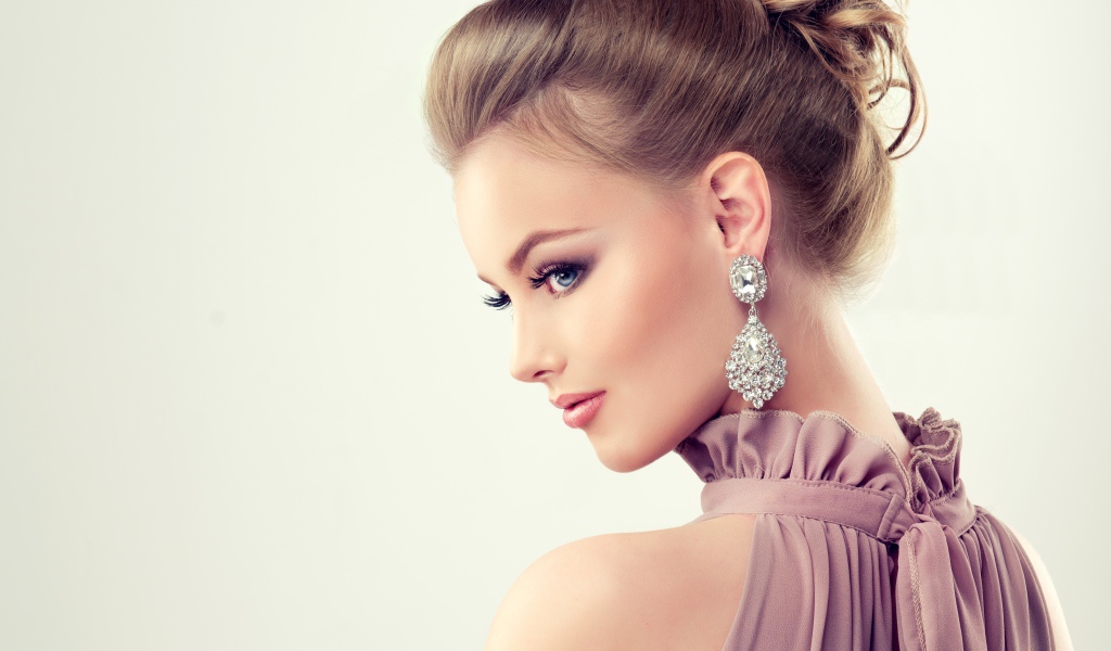 Красивая девушка с макияжем и прической на сером фоне