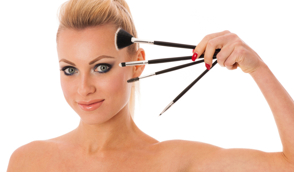 Красивая девушка с кистями для макияжа на белом фоне