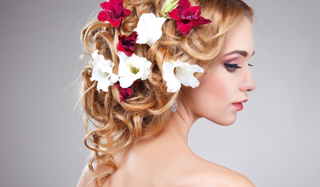 Красивая девушка с цветами петунии в волосах на сером фоне