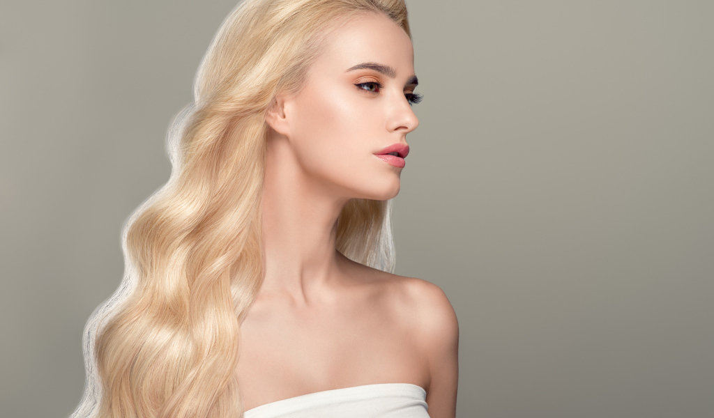 Красивая длинноволосая девушка блондинка на сером фоне