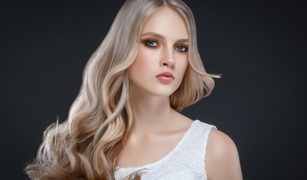 Красивая длинноволосая блондинка с голубыми глазами на сером фоне