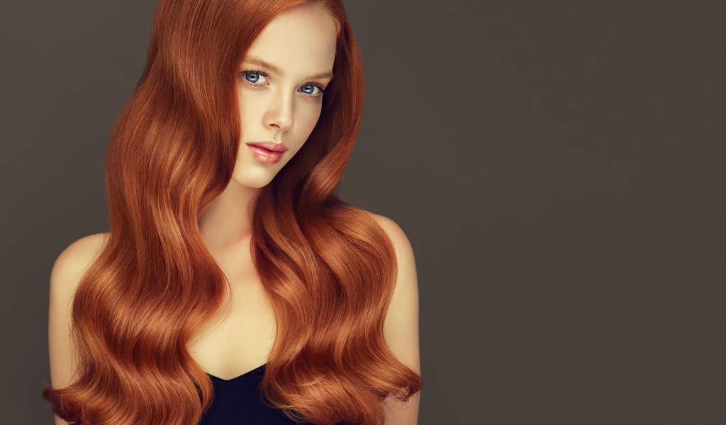 Красивая рыжеволосая голубоглазая девушка на сером фоне