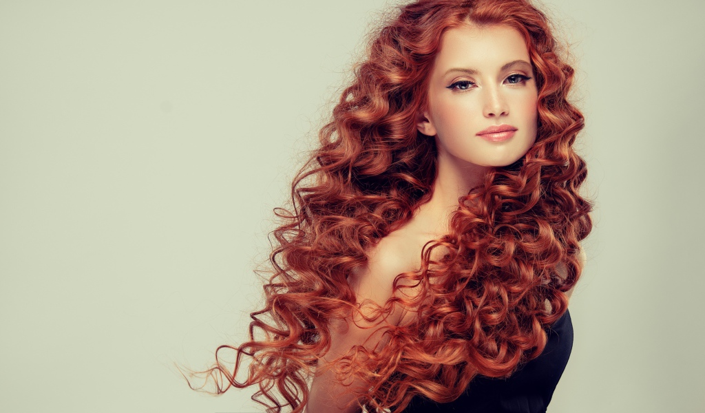 Красивая рыжеволосая девушка на сером фоне