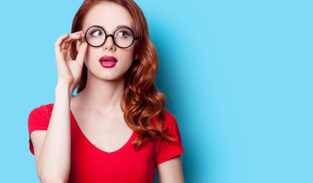 Красивая рыжеволосая девушка в очках на голубом фоне