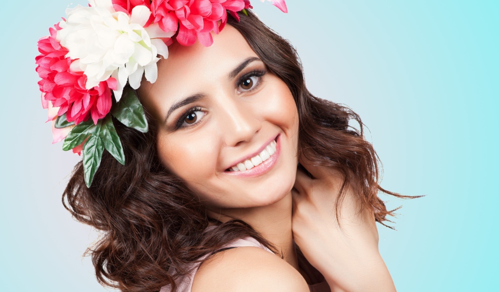 Красивая улыбающаяся девушка с венком на голове на голубом фоне