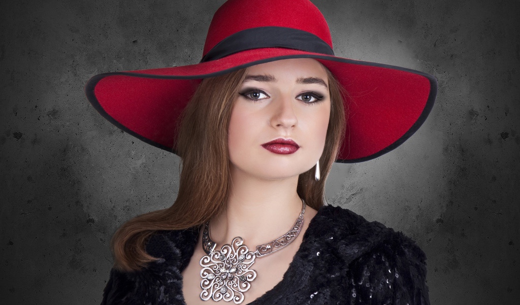 Красивая стильная девушка в красной шляпе с украшением на шее 