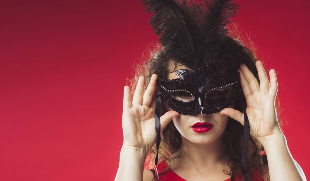 Красивая женщина в черной маске на красном фоне