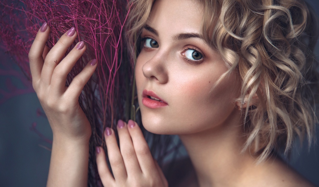 Красивая молодая блондинка с красным растением в руках