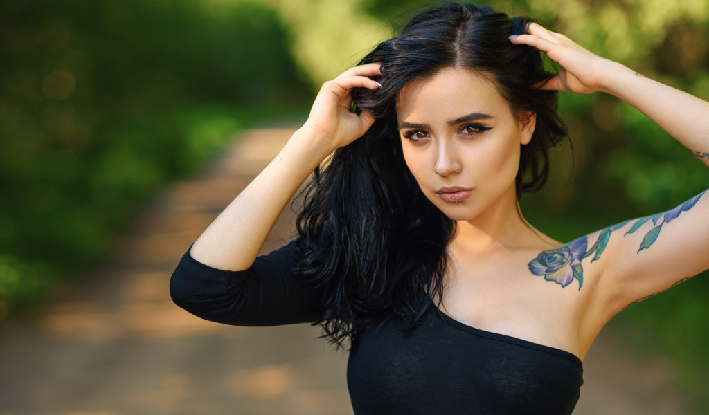 Красивая молодая девушка в черном с татуировкой на руке