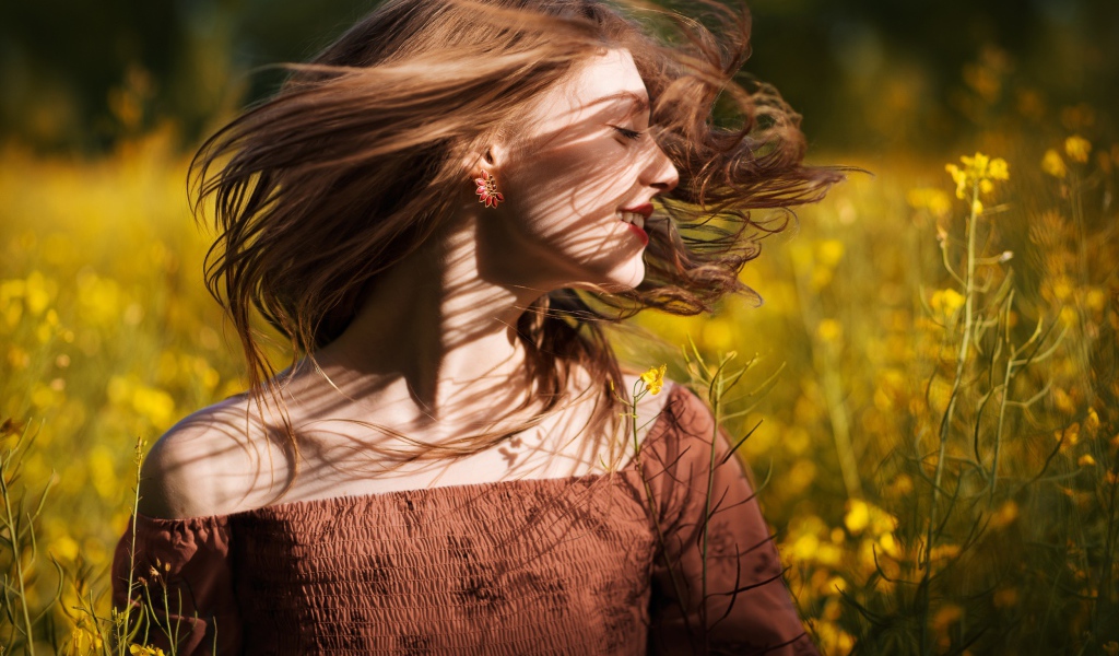 Красивая молодая девушка на поле с желтыми цветами