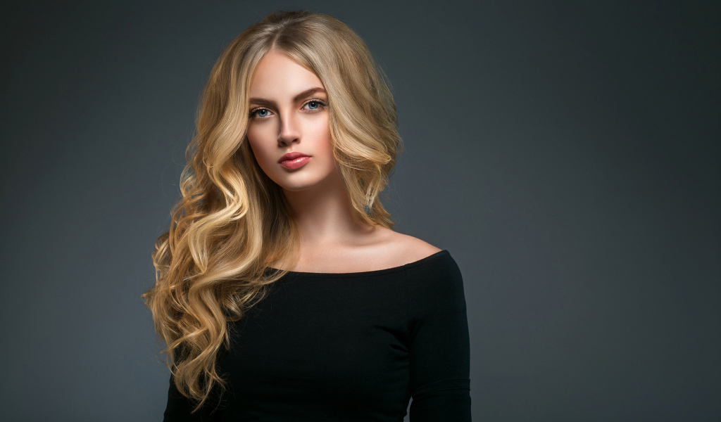 Красивая молодая девушка с длинными волосами в черном наряде на сером фоне