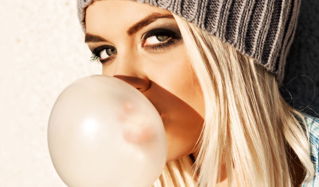 Девушка блондинка с жвачкой во рту крупным планом