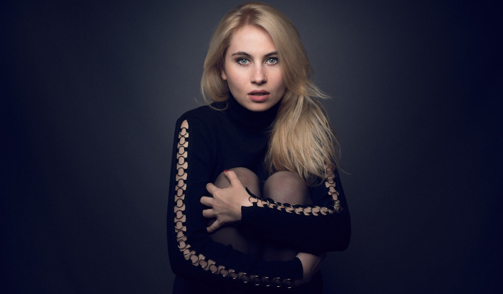 Блондинка в черном наряде на сером фоне