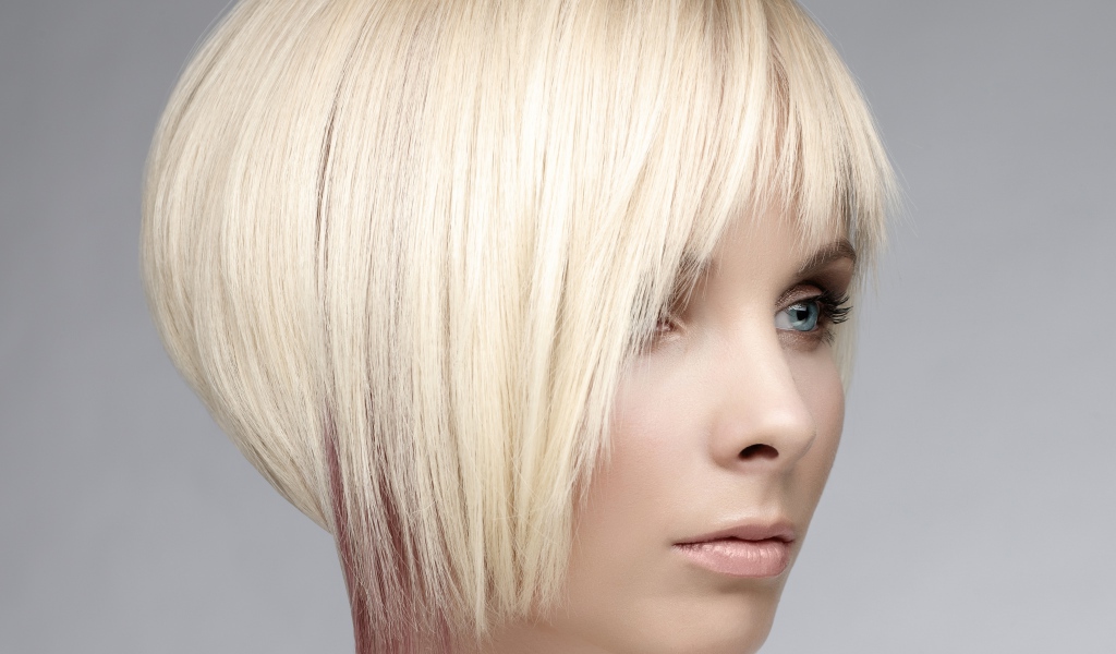 Голубоглазая девушка блондинка с короткой стрижкой на сером фоне